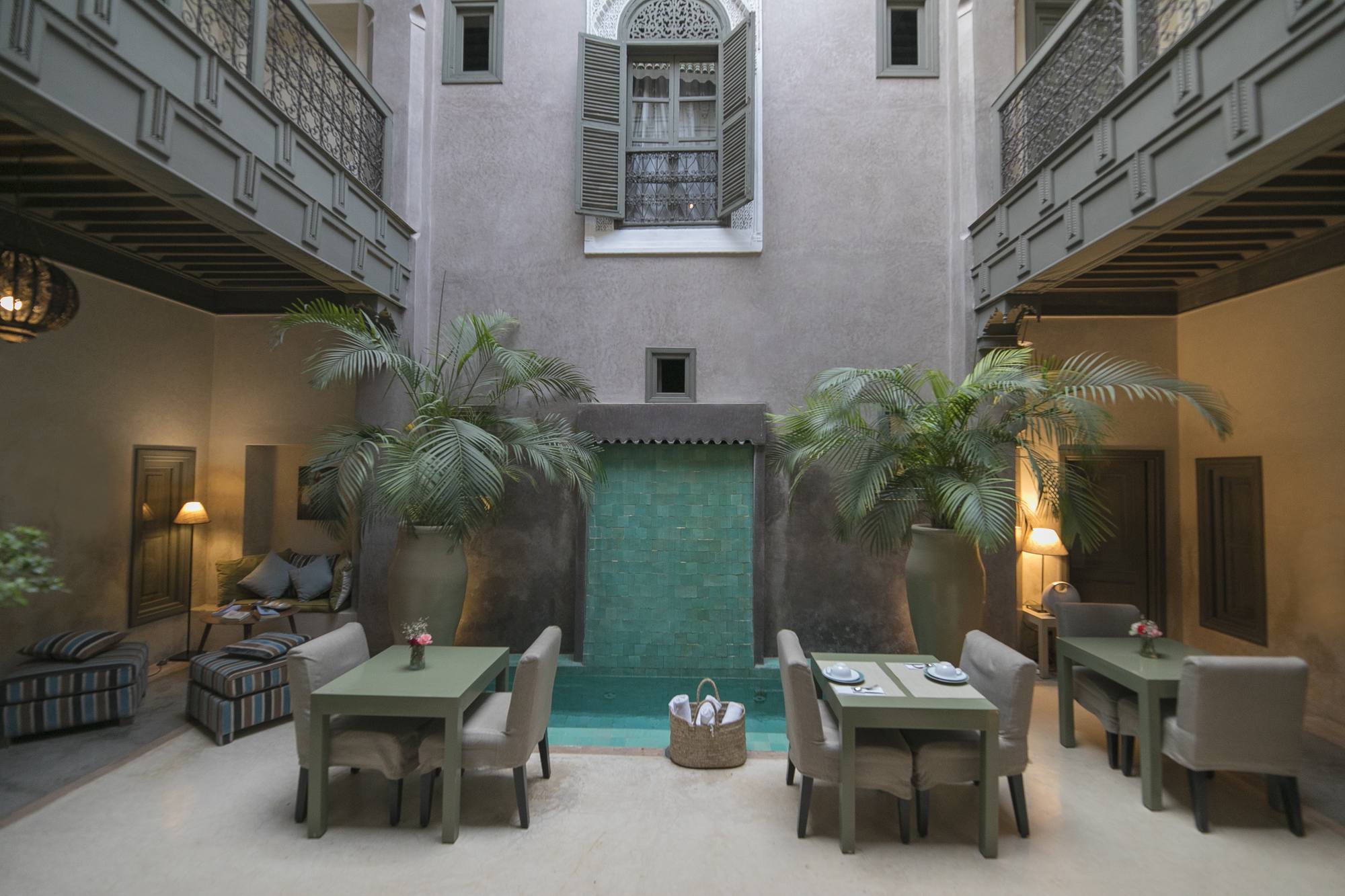 Le patio du Riad Dar One au soir — les tables dressées autour de la piscine, les lanternes allumées sous les galeries