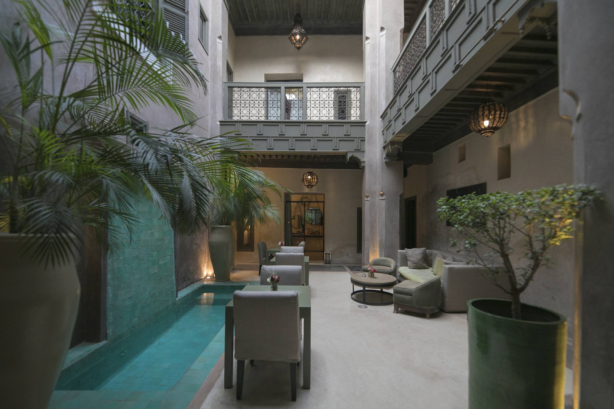 Le patio du Riad Dar One — la piscine vert d'eau au pied des palmiers, sous la galerie à moucharabieh
