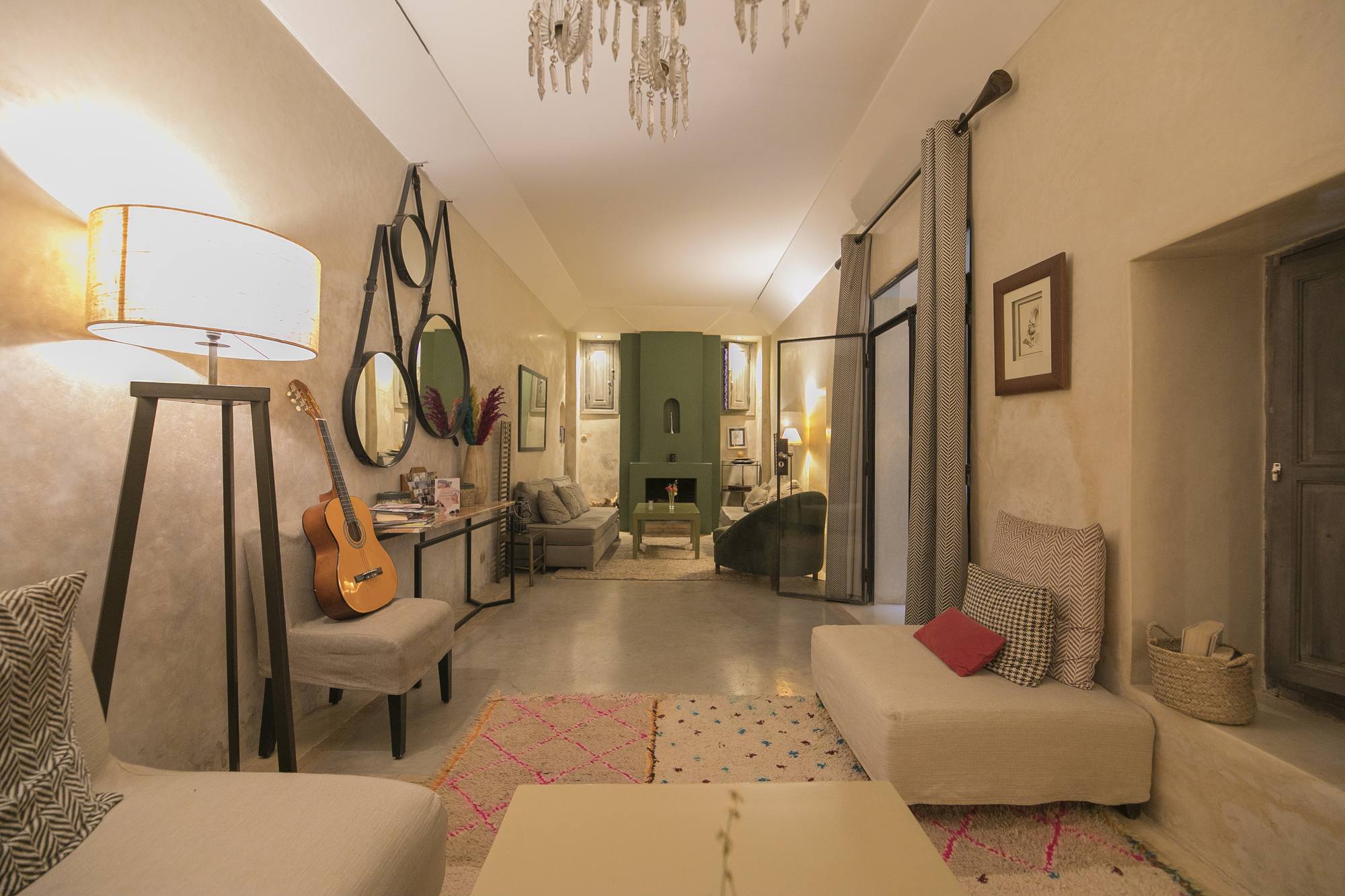 Le grand salon du Riad Dar One — canapés clairs et tapis berbères, guitare et miroirs, la cheminée verte au fond