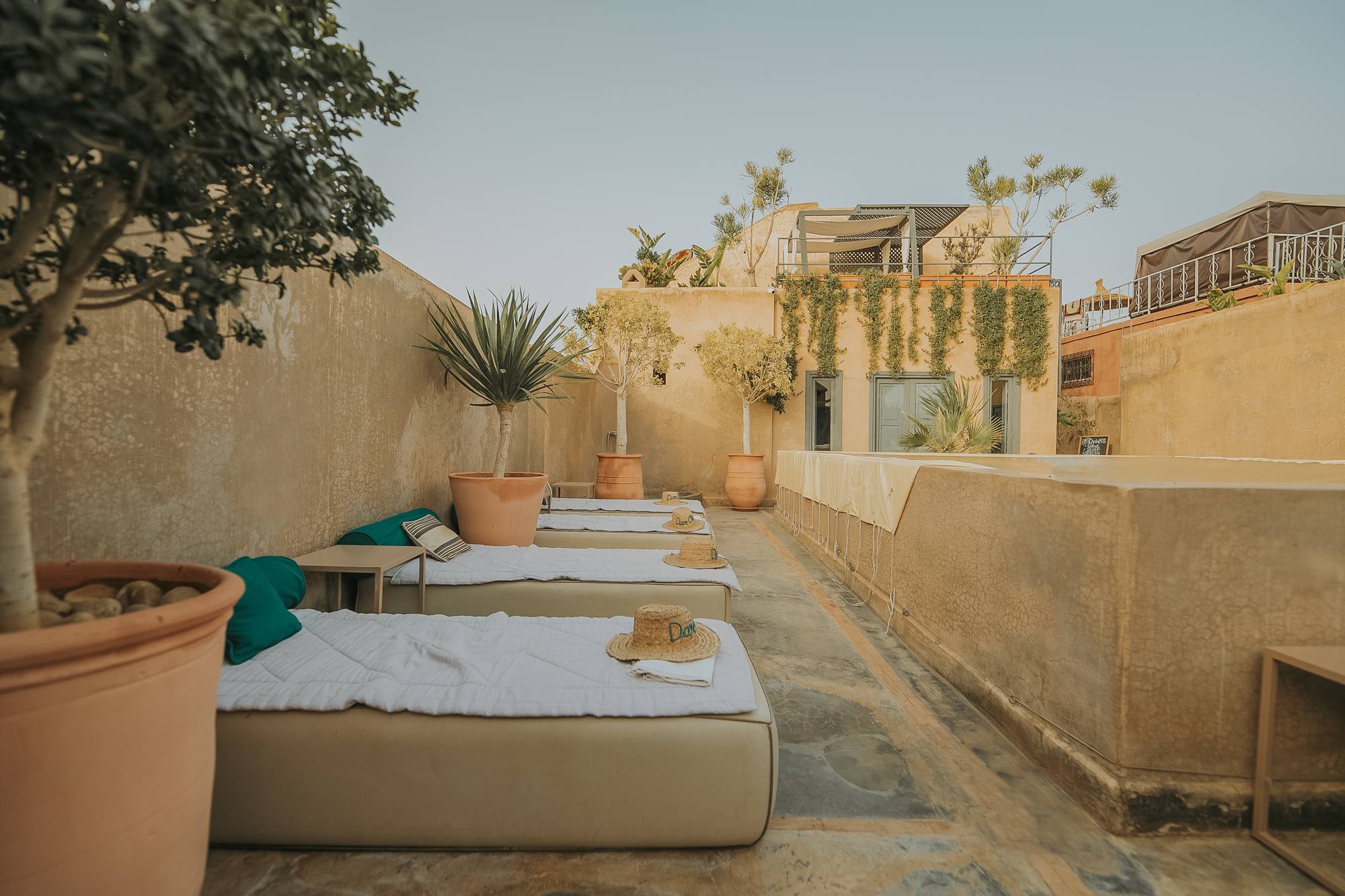La terrasse du Riad Dar One au crépuscule — lits de repos sous les voiles d'ombrage, face aux toits de la médina