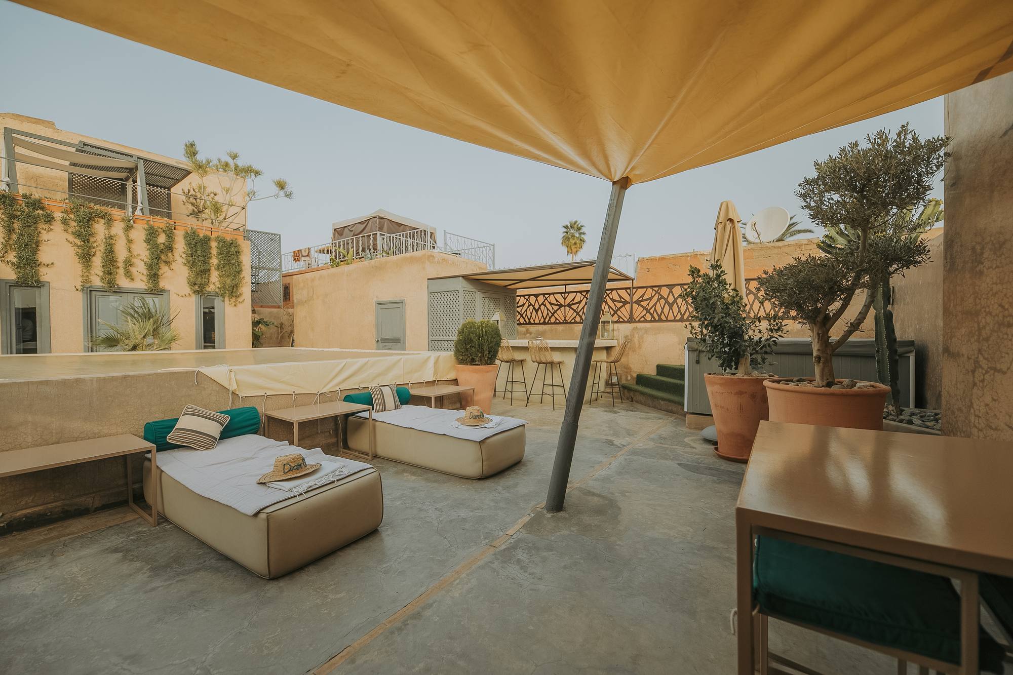 La terrasse du Riad Dar One sous sa voile d’ombrage — lits de repos et bar, les toits de la médina alentour