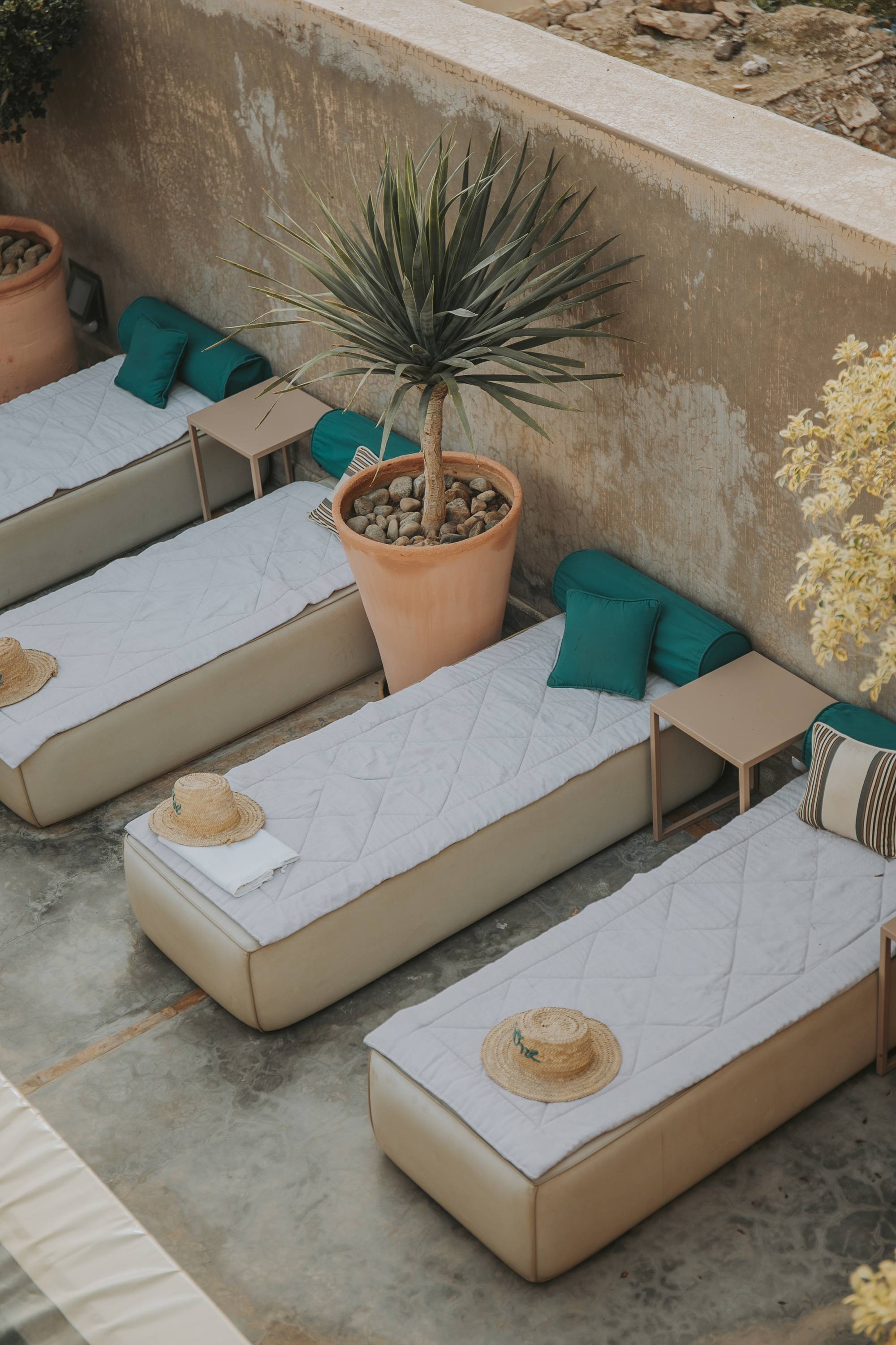 Les lits de repos de la terrasse — matelas blancs, coussins verts et yucca en pot, face aux toits de la médina
