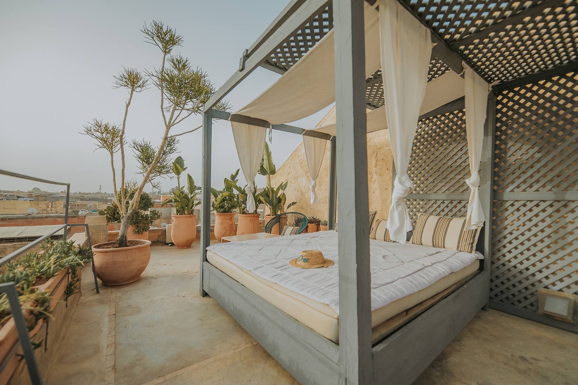Un lit à baldaquin drapé sur la terrasse, face aux toits de la médina