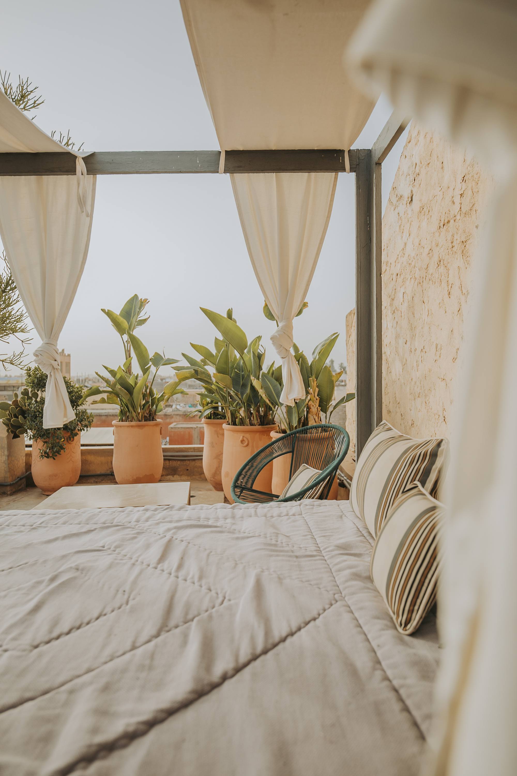 Un lit drapé de voiles blancs sur la terrasse, les toits de la médina en toile de fond